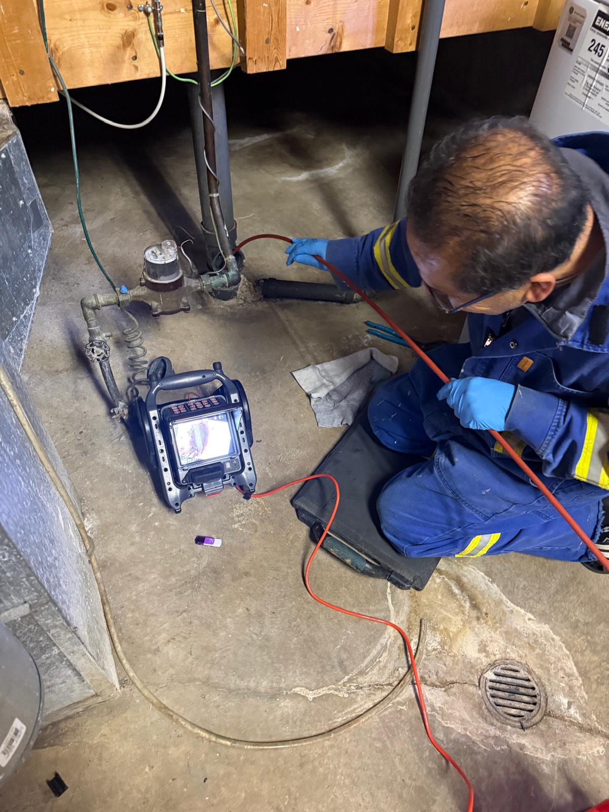 Technician running a sewer inspection camera through a basement floor drain